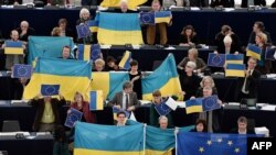 Membri ai Parlamentului European protestînd cu steagul Ucrainei...