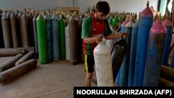 Një punëtor rregullon bombolat e oksigjenit që do të dërgohen në spitale për trajtimin e pacientëve me COVID-19 në Xhalalabad më 11 qershor 2021.