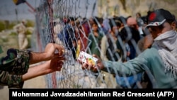 Un soldat iranian oferă sucuri refugiaților afgani de la granița Iranului cu Afganistan. Numărul persoanelor strămutate intern a crescut la 550.000 de la începutul lunii august. 