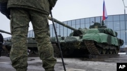 Російський солдат стоїть біля російського танка Т-90 на виставці зброї у Санкт-Петербурзі, Росія, 24 лютого 2024 року