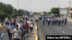 Арысқа қайтудан бас тартып, талаптарын айту үшін Шымкенттің орталық алаңына бара жатқандар мен полицейлер. 27 маусым 2019 жыл.
