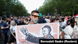Një demonstrues mban një pankartë që përshkruan kryeministrin hungarez, Viktor Orban, si Mao Tse-Dung gjatë një proteste kundër kampusit të planifikuar të universitetit kinez Fudan në Budapest, qershor 2021.