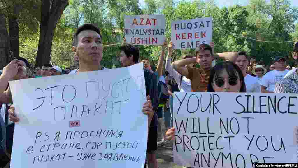 Плакат слева, похоже, является отсылкой к случаю в Уральске, где молодого активиста Аслана Сагутдинова, который вышел на площадь с чистым листом бумаги, задержали полицейские.