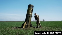 Український військовослужбовець оглядає розгінну ступінь російської балістичної ракети, яка впала в полі на Харківщині, 25 квітня 2022 року 