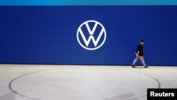 An employee of Volkswagen AG walks past the revised logo 