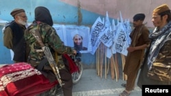 Militantët talibanë shikojnë një poster me portretin e liderit të tyre Mullah Haibatullah Akhundzada. Kabul, 25 gusht 2021. 