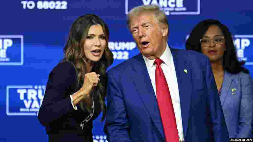 Donald Trump és Kristi Noem dél-dakotai kormányzó a pennsylvaniai Oaksban 2024. október 14-én. Trump, aki kampányában ígéretet tett arra, hogy tömegesen deportálja a papírok nélküli bevándorlókat, várhatóan őt jelöli ki belügyminiszternek. „Kristi nagyon erős volt a határbiztonság terén. Ő volt az első kormányzó, aki a Nemzeti Gárda katonáit küldte Texasba a bideni határválság leküzdésére” – nyilatkozott róla. Noem 2006-ban váltott át a politikára állami képviselőként, miután kisvállalkozóként segített családi gazdaságának vezetésében. A magát hívő kereszténynek valló Noem korábban kritikákat kapott, amiért a dél-dakotai indián törzseket egy kalap alá vette a drogkartellekkel, és visszaemlékezésében arról írt, hogy találkozott Kim Dzsongun észak-koreai vezetővel, valamint hogy elaltatta megvadult kutyáját, amelyet gyűlölt