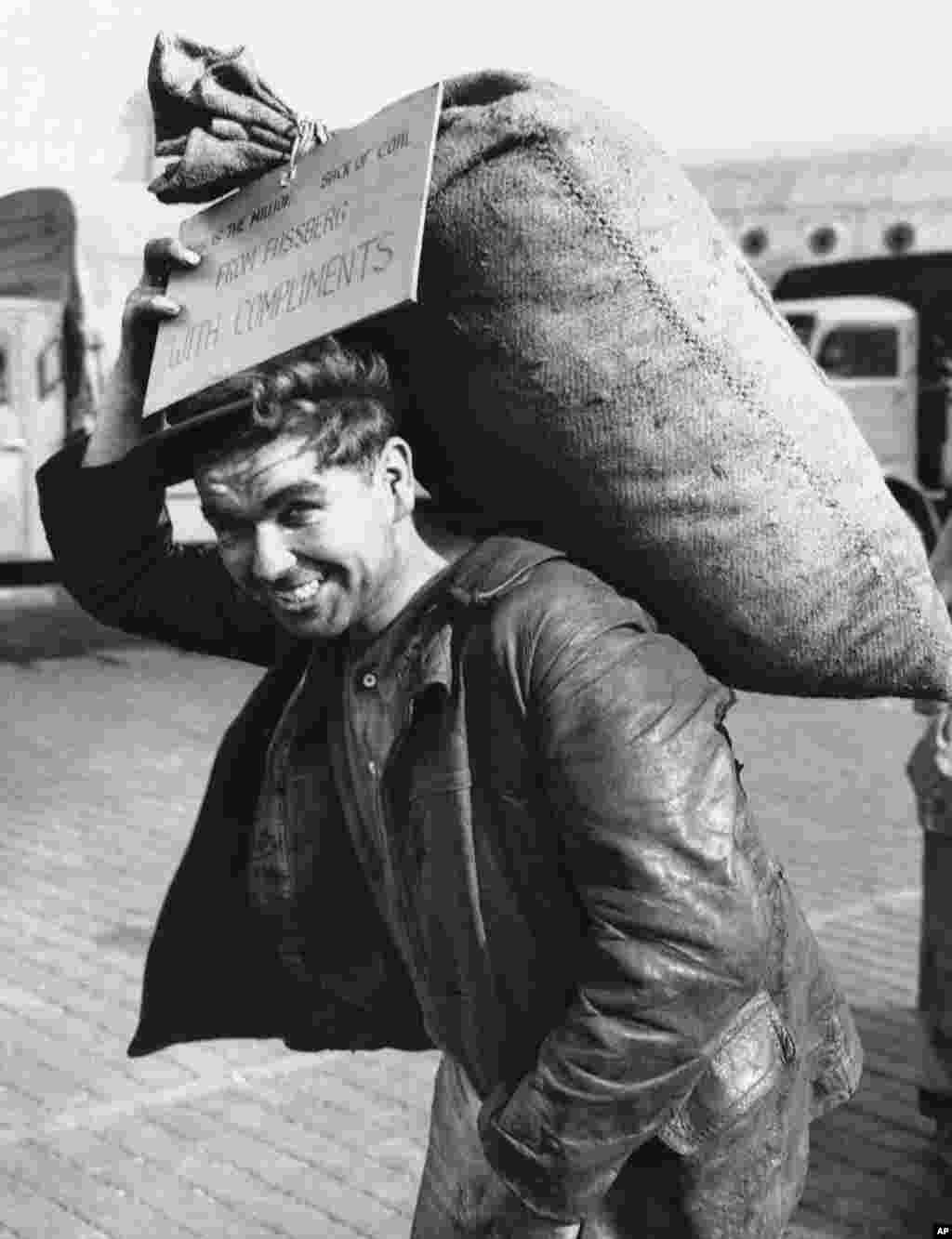 Un muncitor german transportă sacul de cărbune cu numărul 1 milion livrat în Berlinul de Vest, la 20 septembrie 1948. Pe eticheta de pe sac se poate citi "De la Fassberg cu complimente", făcând refeire la aerodromul din zona britanică folosit ca bază pentru ceea ce a devenit cunoscut sub numele de „vagoneții zburători cu cărbune".