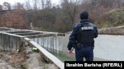 Një oficer i Policisë së Kosovës vështron kanalin e ujit të Ibër-Lepencit, në veri të vendit, ku një shpërthim të premten shkaktoi dëme, duke rrezikuar furnizimin me ujë dhe rrymë, 30 nëntor.