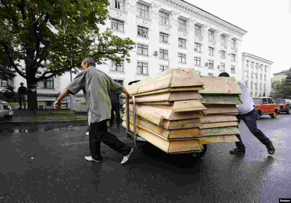 Сепаратисти тягнуть порожні труни для тіл загиблих біля обласного штабу «ЛНР» в Луганську, 18 червня 2014 року