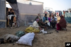 Anëtarët e familjes Abu Jarad, të cilët u zhvendosën nga bombardimet izraelite të Rripit të Gazës, pjekin bukë në një kamp të improvizuar në zonën Muaasi. 1 janar 2024.
