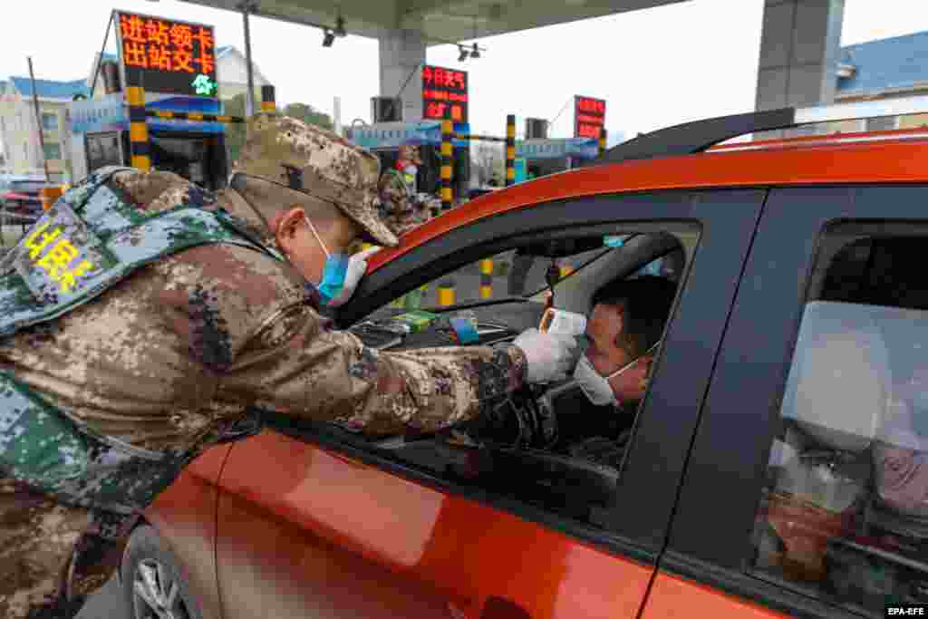 Милиция Ухань қаласының ақылы шоссесіне кіреберіс жерде жолаушылардың дене қызуын тексеріп жатыр. 23 қаңтар 2020 жыл. 