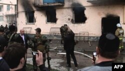 People use their mobile phones to take photos of the scene of a gunfight between Russian security forces and militants in the Chechen capital, Grozny, in April 2011.