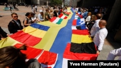 European lawmakers and Ukrainian representatives unfurl a 30-meter-long Ukrainian flag outside the EU Parliament on June 23, the day Ukraine and Moldova were given official candidate status for the bloc.