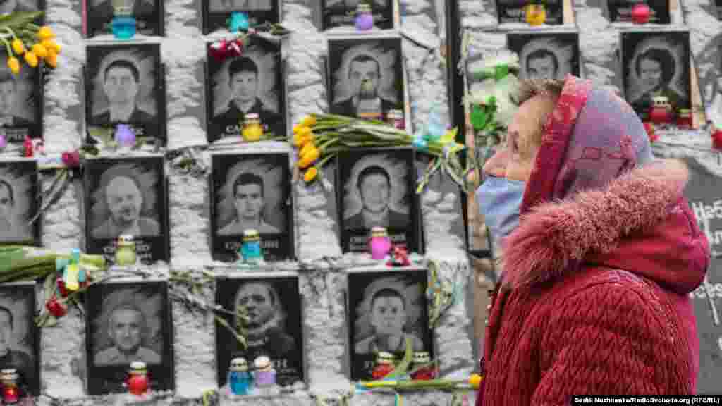Seara de 18 februarie 2021, în fața monumentului din Kiev dedicat martirilor represaliilor din timpul Euromaidanului (Cei o sută de martiri). O femeie aduce onoruri celor 104 persoane ucise în timpul demonstrațiilor anti-guvernamentale din 2014 