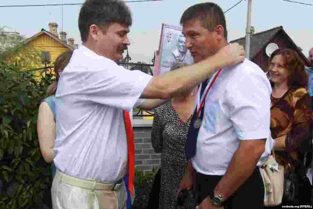Паэт Міхась Скобла ўручае памятны мэдаль унуку Ларысы Геніюш Міхасю Геніюшу, які прыехаў зь Беластоку.
