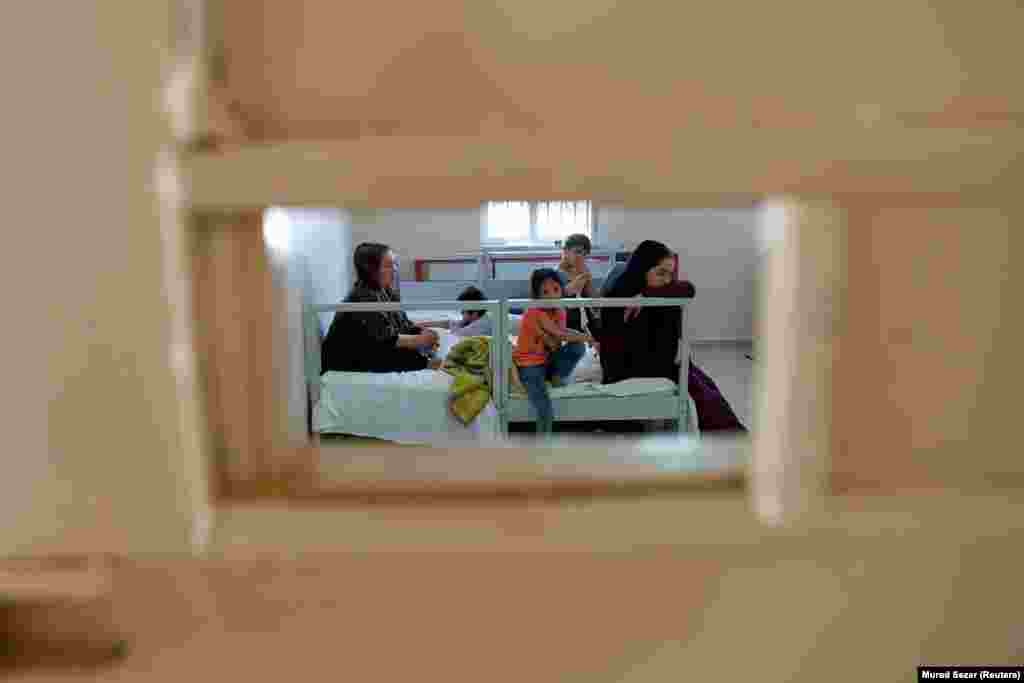 Një familje nga Afganistani, që është arrestuar nga forcat turke për shkak të kalimit të paligjshëm të kufirit, qëndron në një qendër të migrantëve në qytetin turk Van më 22 gusht 2021.